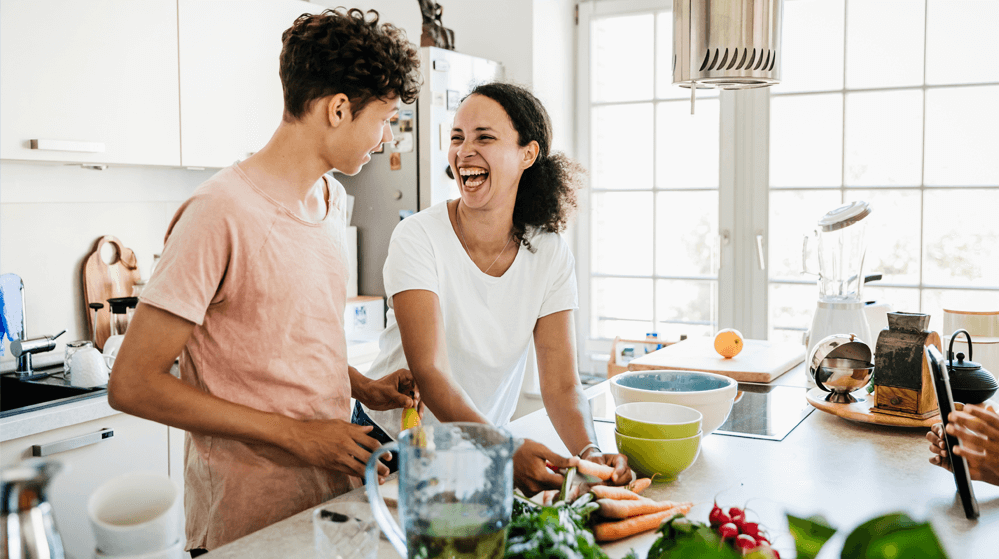 Une femme et un homme rient ensemble dans une cuisine, créant une atmosphère joyeuse et conviviale
